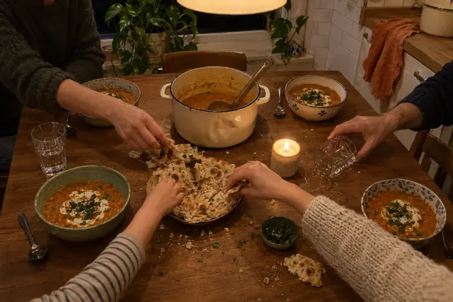 Von oben: vier Schalen Linsensuppe mit Joghurt, Hände greifen nach Fladenbrot, eine Kerze brennt.